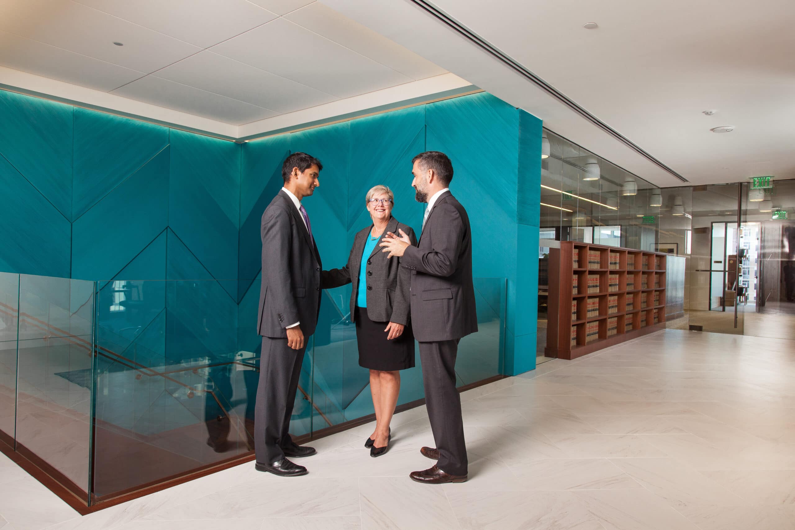 Three attorneys having a discussion in a law office hallway.