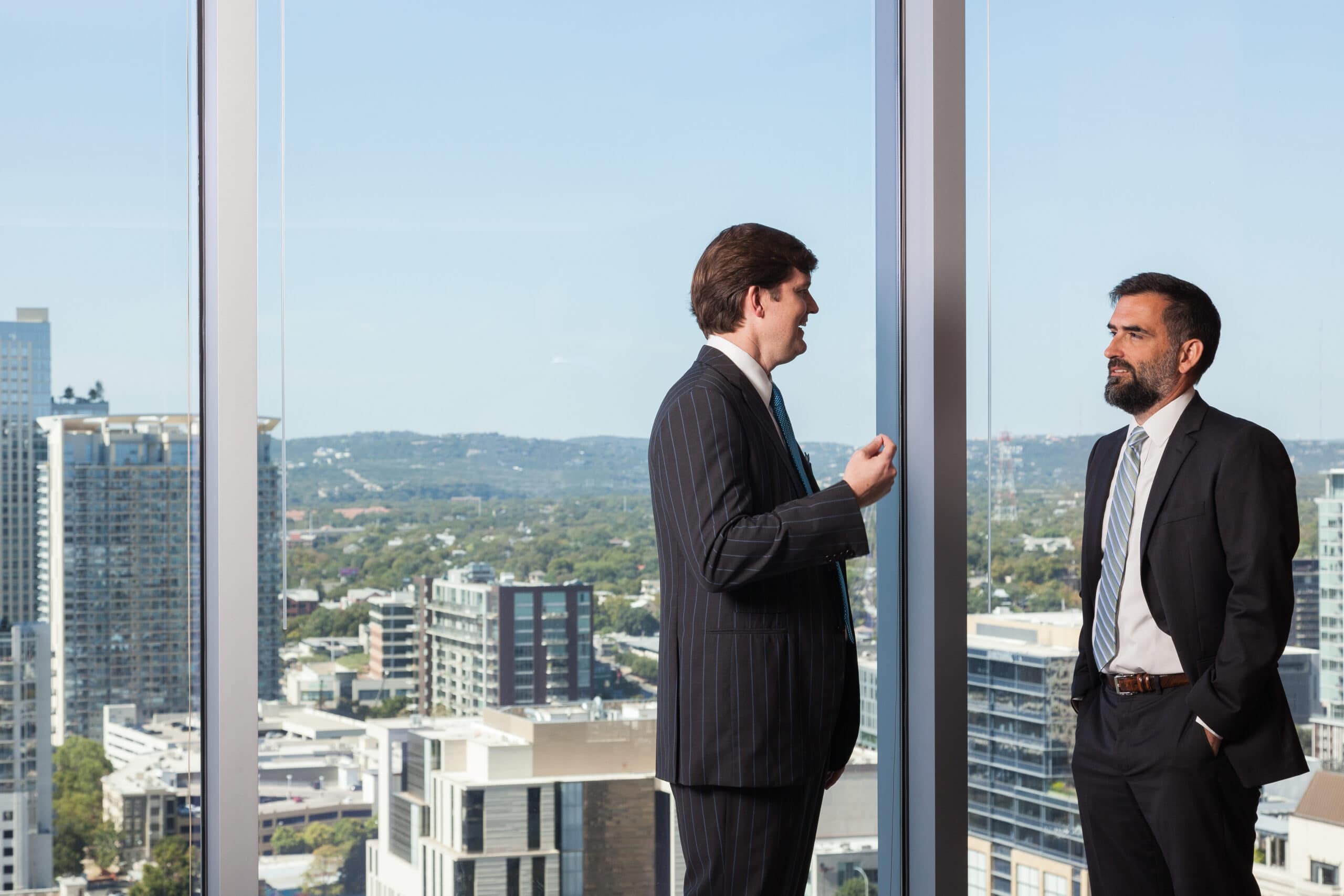 Two men having a conversation with downtown behind them.